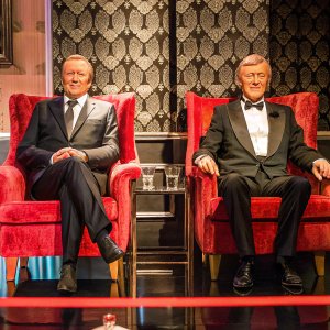 Formal photo of David Frost and Michael Parkinson, seated on plush velvet chairs, at the British Academy Television Awards. The background is a classic patterned wallpaper.