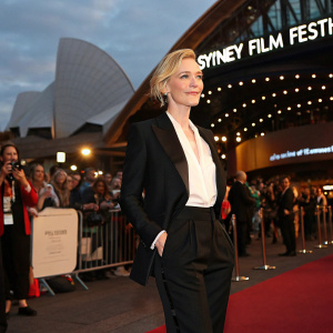 Cate Blanchett at the Sydney Film Festival premiere. Dressed in a black tailored suit and white blouse. Surrounded by bustling crowds outside the event venue.