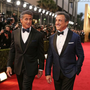 Sylvester Stallone and Frank Stallone at an award show. Wearing formal suits. Red carpet, flashing cameras.