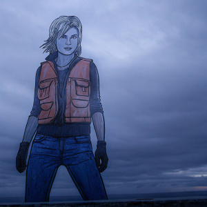 Profile picture of Tracer from Overwatch. Blonde hair, orange vest with functional pockets, blue jeans.
