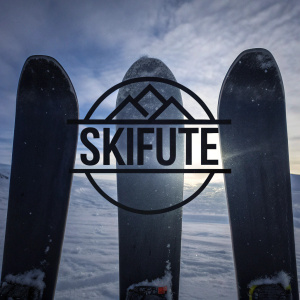 A sleek, modern logo for Skifuté. Central focus is the bold word 'SKIFUTÉ' encased within a rugged mountain peak emblem. Below the emblem, skis are elegantly displayed. The design employs stark black against a pristine white backdrop, highlighting a bold and graphic aesthetic.