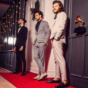 Zayn Malik, Liam Payne, Harry Styles on the Grammys red carpet, against a backdrop of shiny gold trophies and LED lights.
