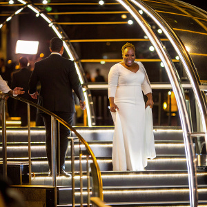 Emeli Sande at a Grammy Awards ceremony. Wearing a white, floor-length gown. Beaming smile