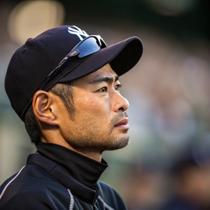 Ichiro Suzuki, Asian baseball player, intense focus. Dark cap, athletic gear. Close-up shot, high-res. Soft shadows, blurred background. Emphasizing his cap and features.