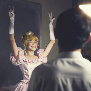 Serena, the cheerful protagonist of Sailor Moon, giving a peace sign. Pink frilly dress and tiara
