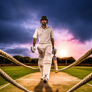 Ben Stokes, cricketer, walking confidently on a cricket ground. Dark blue sky, sun setting in the background