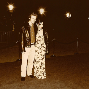 Hayden Christensen, dressed in a black leather jacket, and Bai Ling, in a floral dress, posing at a Hollywood event.