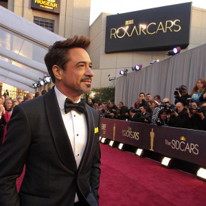 Robert Downey Jr., in a tuxedo, gracing the Oscars red carpet. Surrounded by fans and paparazzi, the Hollywood sign in the background.