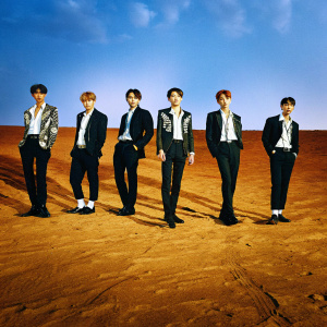 Monsta X, the renowned Korean boy band, dressed in elegant black and white attire. They stand in a dynamic group pose against a simple backdrop, showcasing their diverse hairstyles and unique styling elements.