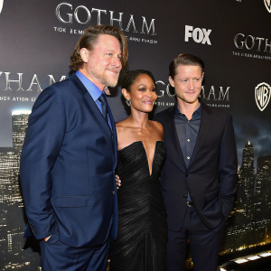 Donal Logue, Jada Pinkett Smith, and Benjamin McKenzie at a glamorous premiere event. Dark cityscape backdrop with Gotham logos. All actors in formal wear. Donal Logue in navy suit and blue shirt, Jada in black gown, Benjamin in dark suit and subtle shirt.