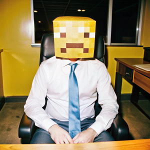 takım elbiseli iş adamı ofisinde oturuyor yüzünde minecraft maskesi var