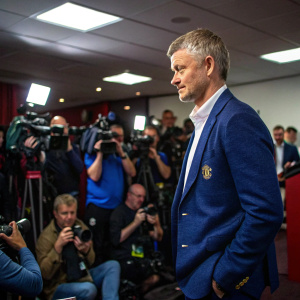 Ole Gunnar Solskjaer, manager of Manchester United, in a sharp blue blazer, at a press conference. Crowded room with cameras flashing.
