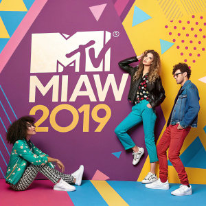 A vibrant promotional image for MTV Miaw 2019. The colorful scene features a dynamic mix of personalities in casual outfits against a backdrop of geometric shapes. The design includes a blend of Spanish and English text, creating an engaging visual composition.