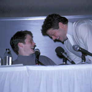 A candid shot of Elijah Wood and Sean Astin laughing during a press conference.