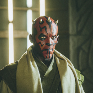Intense close-up of Darth Maul's face from Star Wars. Dark background highlights detailed facial features and red tones.