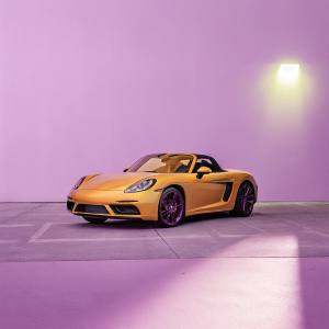 A stunning orange Porsche 718 Boxster S Ceramic Pro parked outside a well-lit Ceramic Pro store. The car's sleek design and modern aesthetic stand out against the urban backdrop.