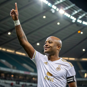 Andre Ayew, bald soccer player, celebrating with raised hand. Indoor stadium background.