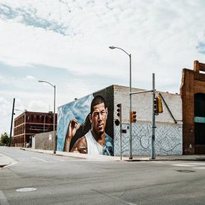 Nate Diaz, UFC fighter, in a vibrant street art mural. Graffiti-styled background, bold colors, urban setting