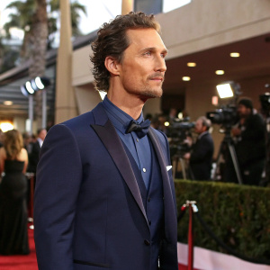 Matthew McConaughey in a stylish navy blue suit, looking composed. At a high-profile Hollywood awards show.