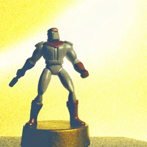 Action figure of Ulysses 31's hero. Standing in dramatic battle pose. Detailed musculature and dynamic stance. Brown color with textured surface. Positioned on a sturdy brown base.