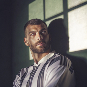 Leonardo Spinazzola, soccer player, intense look, well-groomed beard, short hair. White and black Juventus FC jersey. Solid green background