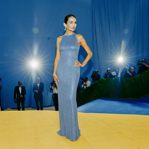 Camilla Belle at a glamorous gala, dressed in a silver, sleeveless gown with intricate beading. Confident pose, styled hair, on a crowded red carpet.