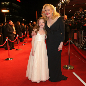 Cathy Moriarty with a young girl in a white dress. They pose at the War Horse premiere on the red carpet.