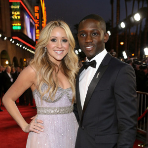 Amanda Bynes and Elijah Kelley at an awards show. Both dressed in designer gowns and tuxedos. Flashing lights and crowds in the background.