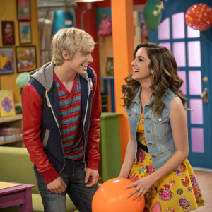 Scene from Austin & Ally, main characters Austin Moon and Ally Dawson in casual outfits, interacting playfully. Brightly colored set design, indoor studio with various props scattered around.