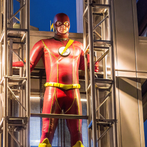 Wally West, aka The Flash, standing heroically in a vividly colored costume. Dynamic pose, set against an uncluttered, solid blue backdrop. Focused expression, with the iconic lightning bolt symbol prominently displayed on his chest.