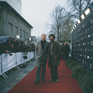 Boris Becker and Noah Becker attending Mercedes-Benz Fashion Week in Berlin. They are on the red carpet, posing for photos in front of a backdrop filled with logos and banners.