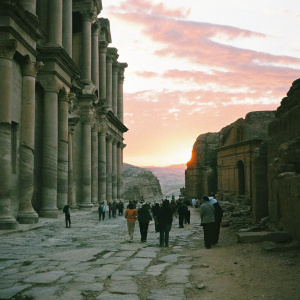 Tourists walking among the ancient stone structures of Petra. Vibrant sunset casting shadows