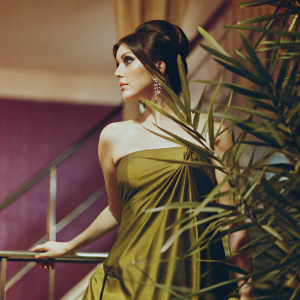 Photogenic snapshot of Tanya Roberts at glamorous event. Elegant dark hair, serious demeanor. Wearing a stunning green dress, against a rich purple backdrop.