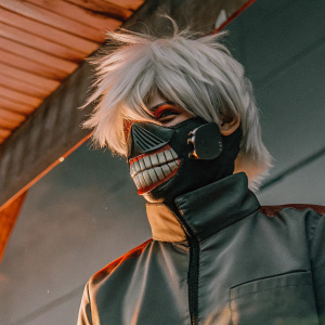 Ken Kaneki from Tokyo Ghoul. He's wearing a mask that partially covers his face, showing off sharp teeth. Wears white, spiky hair. Dark background, mostly red tones