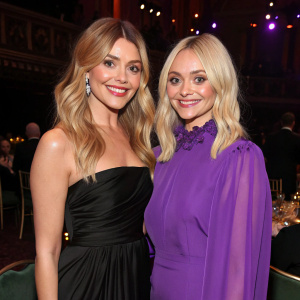 Holly Willoughby, blonde hair, black gown, posing with Fearne Cotton, multi-toned hair, purple blouse, at event.