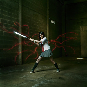 Chihaya Mifune, from Persona 5, depicted in a dynamic action pose. She wields a large electrified weapon. Fiery red abstract shapes surround her, casting a dramatic aura.