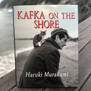 Book cover for 'Kafka on the Shore' by Haruki Murakami. Enigmatic man with a cat. The cover is black and white, with red lettering.