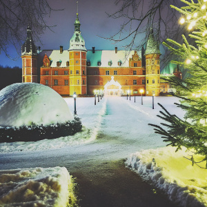 Frederiksborg Castle illuminated at night. Snow-covered grounds, winter wonderland atmosphere