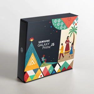Innovative packaging for Samsung Galaxy J5 Prime. Festive theme with people in traditional outfits against vibrant geometric shapes. Sleek, modern box design featuring Galaxy J5 Prime logo prominently.