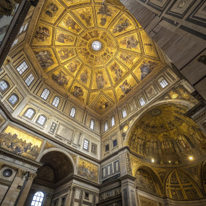 A detailed view of the intricate ceiling inside the Florence Baptistery. The mosaic artwork gleams in vibrant gold hues.