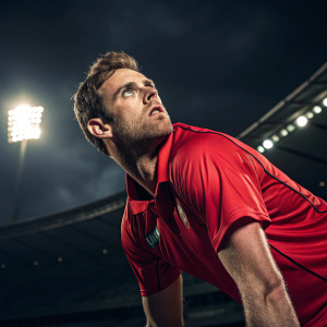 Peter Borren, cricket player, intense pose, wearing red athletic jersey. Dark stadium background, artificial lighting, photo style close-up, high resolution.