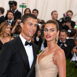 Cristiano Ronaldo and Irina Shayk attending the Met Gala. Wearing black tuxedo and elegant dress respectively. Crowded event with paparazzi flashing