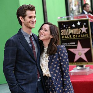 Andrew Garfield and Shannon Woodward, smiling, standing in front of a green backdrop with Hollywood Walk of Fame stars.