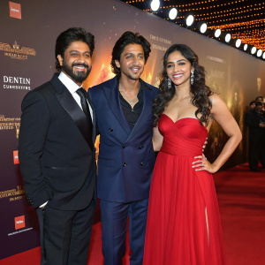Shahrukh Khan, Bedabrata Pain, and Vega Tamotia at the film premiere. Red carpet event, promotional backdrop, warm stage lighting.