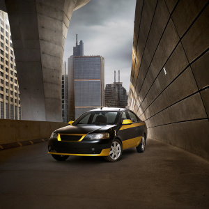 Modern Proton Saga Anniversary Edition car, glossy black with vibrant yellow accents. Posing in a futuristic cityscape
