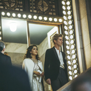 Salma Hayek and Austin Butler attending the Met Gala. They are standing in front of a grand entrance adorned with intricate designs and lights.