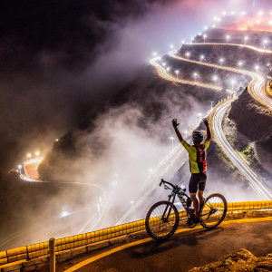 Jonathan Caicedo Cepeda, the winning cyclist from Ecuador, celebrating his victory at the 103rd Giro d'Italia. Wearing a vibrant EF Pro Cycling jersey, raising his arm in triumph on a misty mountain road.