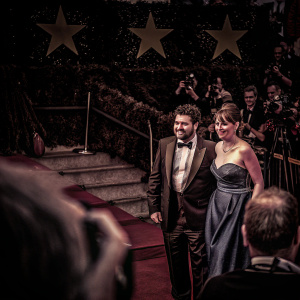 David Krumholtz and Vanessa Britting at the Met Gala. David in a black tuxedo, Vanessa in a blue strapless gown. Stars, paparazzi, and red carpet in the background.