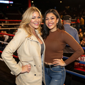 Shanna Moakler and Atiana Cecilia de la Hoya smiling at a boxing event. Shanna in a light beige jacket, Atiana in brown top and jeans. Crowded backdrop
