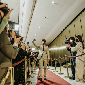 Andrew Garfield signing autographs and posing for photos at the film premiere. Red carpet event with flashing cameras and fans.